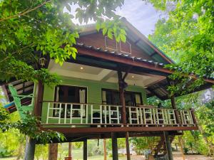 a green house with a balcony in the trees at Baan Moonchan House in Chaloklum