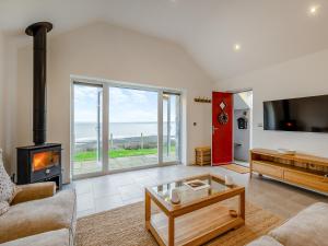 sala de estar con chimenea y vistas al océano en Y Beudy Gwydir, en Trevor