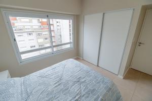 a bedroom with a bed and a large window at Check and Home - Entre Ríos - 4 Huéspedes a estrenar a 100 mts Plaza Colón y Casino in Mar del Plata