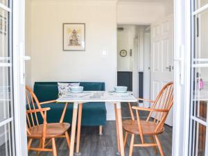 a dining room table and chairs with a green couch at Beam Cottage in Flamborough