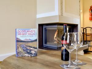 una botella de vino y una copa en una mesa con chimenea en Jessamine Cottage, en Blairgowrie