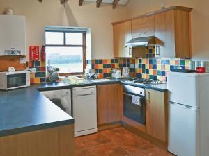 a kitchen with wooden cabinets and a white refrigerator at Meadow Cottage - Uk45882 in Flamborough