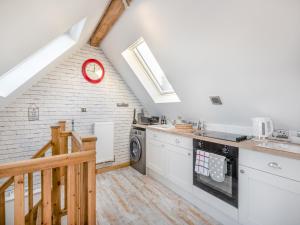 a kitchen with white appliances and a red clock on the wall at Rose Cottage in Peldon