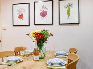 a dining room table with a vase of flowers at Woodbine Cottage in Whittington
