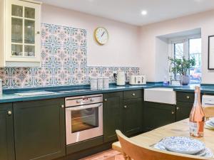 a kitchen with green cabinets and a table at Woodbine Cottage in Whittington