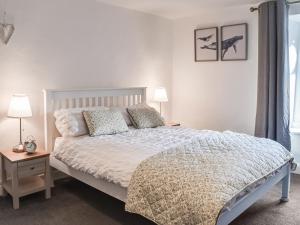 a bedroom with a white bed with pillows at Woodbine Cottage in Whittington +9 photos