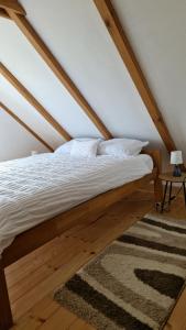 a bed with white sheets and a rug in a attic at Kuća za odmor Josipa in Klanjec +29 photos