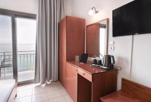 a hotel room with a desk with a television and a balcony at Anesis in Platamonas