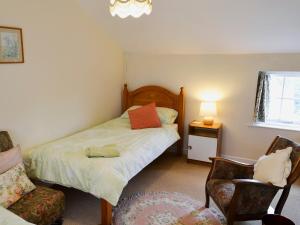 ein kleines Schlafzimmer mit einem Bett und einem Stuhl in der Unterkunft Watercolour Cottage in Lerryn + 6 Fotos