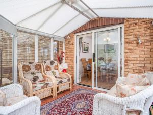 un salón acristalado con sillas de mimbre y mesa en Squirrels, en Teignmouth