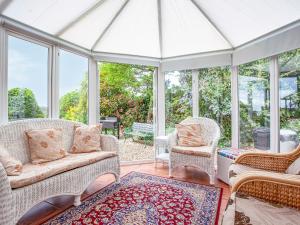 un porche cubierto con muebles y ventanas de mimbre en Squirrels, en Teignmouth 18 fotos más