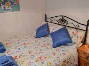 a bed with two blue pillows on top of it at Wild Flower Cottage in Youlgreave +3 photos