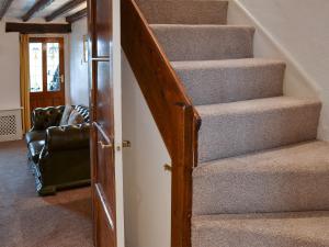 a staircase in a house with a chair next to it at Wild Flower Cottage in Youlgreave