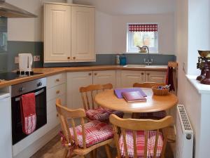 a kitchen with a table and chairs with a book on it at Wild Flower Cottage in Youlgreave