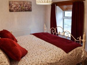 a bedroom with a bed with red pillows and a window at Wild Flower Cottage in Youlgreave