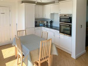 a kitchen with white cabinets and a table and chairs at Flat 18 Pochin House in St Austell