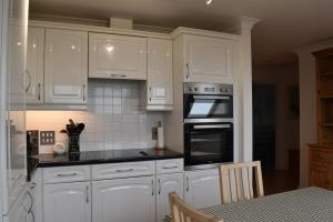 a kitchen with white cabinets and a stove top oven at Flat 18 Pochin House in St Austell +5 photos