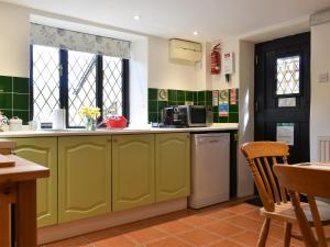 a kitchen with green cabinets and a window at Barn Court Cottage in Washfield