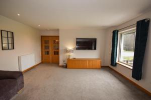 a living room with a couch and a tv on the wall at Aurora - Self Catering, Kirkwall, Quiet Location with Luxury Hot Tub in Orkney