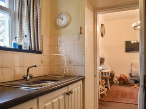 a kitchen with a sink and a clock on the wall at Beeches in Windermere