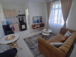 a living room with a couch and tables and a tv at Belaire Bnb one bedroom in Thindigua kiambu road in Kiambu