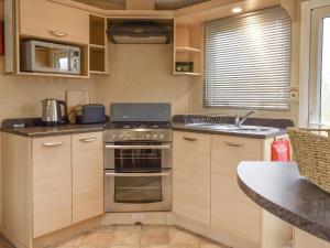 a kitchen with a stove and a sink at Doggy Dell in Motcombe