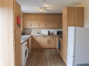 una cucina con mobili in legno e un frigorifero bianco di Corner Cottage a Girvan