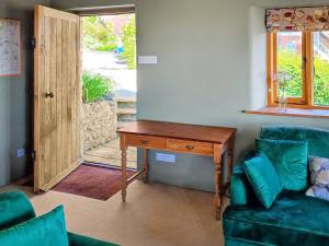 Zimmer mit einem Schreibtisch, einem Sofa und einem Tisch in der Unterkunft Homer's Cottage in Cucklington