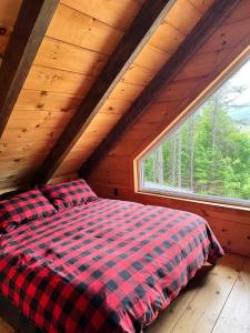 a bed in a room with a large window at Chalet bois rond, Spa, rivière & nature in Lac-aux-Sables +22 photos
