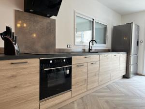 een keuken met een zwarte oven en houten kasten bij La Petite Saulaie - Proche circuit 24h - 6 pers in Changé +10 foto's