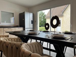 een eettafel met stoelen en een groot raam bij La Petite Saulaie - Proche circuit 24h - 6 pers in Changé