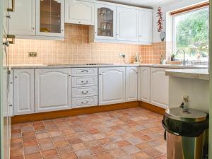 a kitchen with white cabinets and a tile floor at Heather Cottage in Saint Erth +5 photos