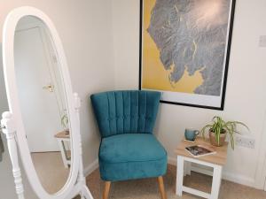 ein blauer Stuhl neben einem Spiegel in der Unterkunft Hillside Farm Cottage in Grange Over Sands + 4 Fotos