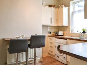 a kitchen with white cabinets and a table with chairs at White Rose Apartment in Bridlington