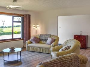 a living room with two couches and a table at Lowesmuir Cottage in Cumnock