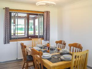 a dining room with a table and chairs and a window at Lowesmuir Cottage in Cumnock