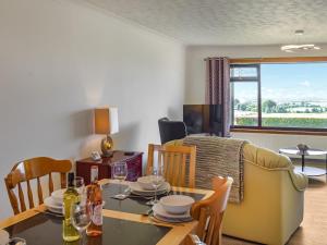 a dining room and living room with a table and chairs at Lowesmuir Cottage in Cumnock
