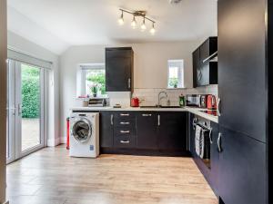a kitchen with black cabinets and a washer and dryer at Riviera Cottages in Sewerby