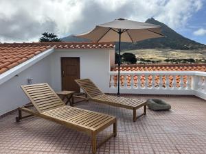 a patio with two chairs and an umbrella at Sailor House - By Wehost in Porto Santo