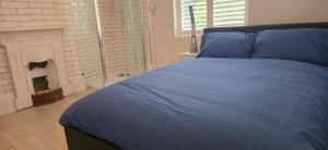 a bed with a blue comforter and a fireplace at 8 Guests - Free Parking - Full Equipped House in Saint Helens