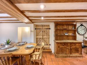ein Esszimmer mit einem Holztisch und einer Uhr in der Unterkunft Gladwyn Cottage in Sutton Benger + 17 Fotos