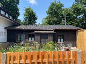 a black house with a fence in front of it at Gästehäuschen mit Kamin in Gauting