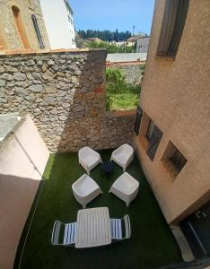 グリュイッサンにあるAu cœur du village de Gruissanの草の上に置かれた4つの白いスツール