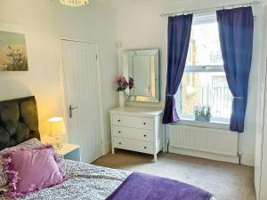 a bedroom with a bed and a mirror and a window at Rutland Retreat in Filey +4 photos
