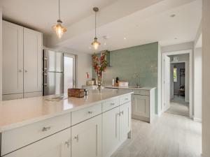a kitchen with white cabinets and a large island at Little Dab in Brancaster