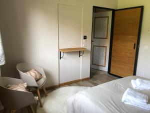 a bedroom with a bed and two chairs and a door at Independent studio in a chalet in Mont-Saxonnex