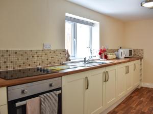 a kitchen with white cabinets and a sink and a window at Winnies Cottage in Belford