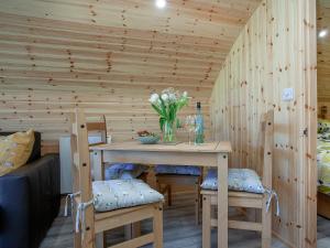 a wooden room with a table with chairs and flowers at Glamping Pod 2 in Ipplepen