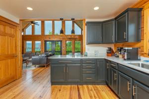 a kitchen with black cabinets and wooden floors at Whiskey Hills - Newly Remodeled Luxury Cabin with Hot Tub, Incredible Views close to Asheville, walk to Hatley Pointe & Ski! in Swiss