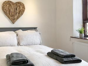 a bed with two towels on it with a heart on the wall at Fisherman's Cottage in Plymouth